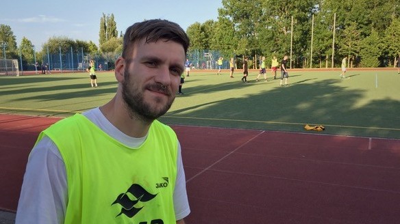 Porträt eines jungen Mannes mit Bart und Nasen-Piercing am Rande eines Fußballplatzes