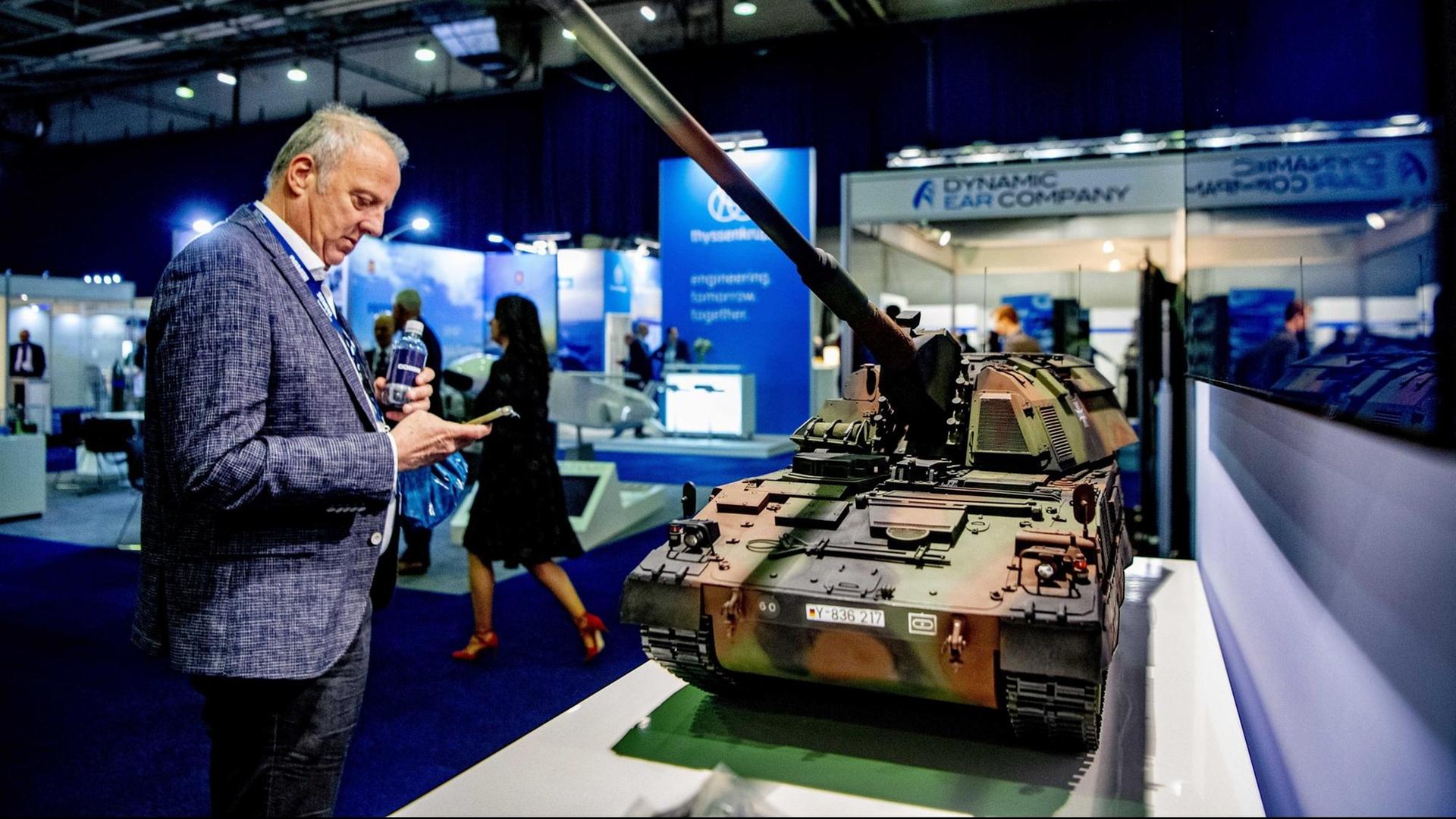 Ein Messebesucher steht vor dem Modell eines Panzers der deutschen Bundeswehr