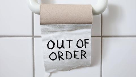 eine fast leere Toilettenpapierrolle auf derem letzten Blatt "out of order" steht