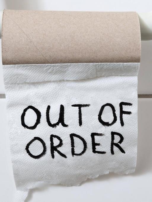 eine fast leere Toilettenpapierrolle auf derem letzten Blatt "out of order" steht