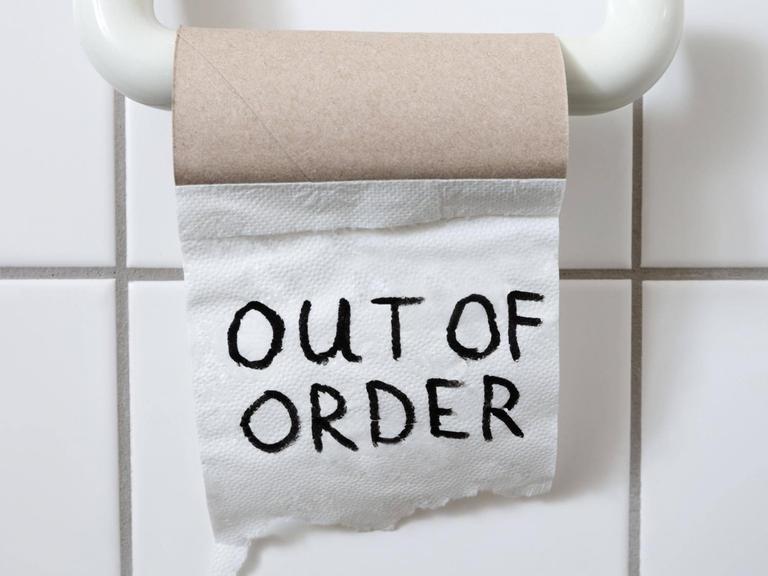 eine fast leere Toilettenpapierrolle auf derem letzten Blatt "out of order" steht