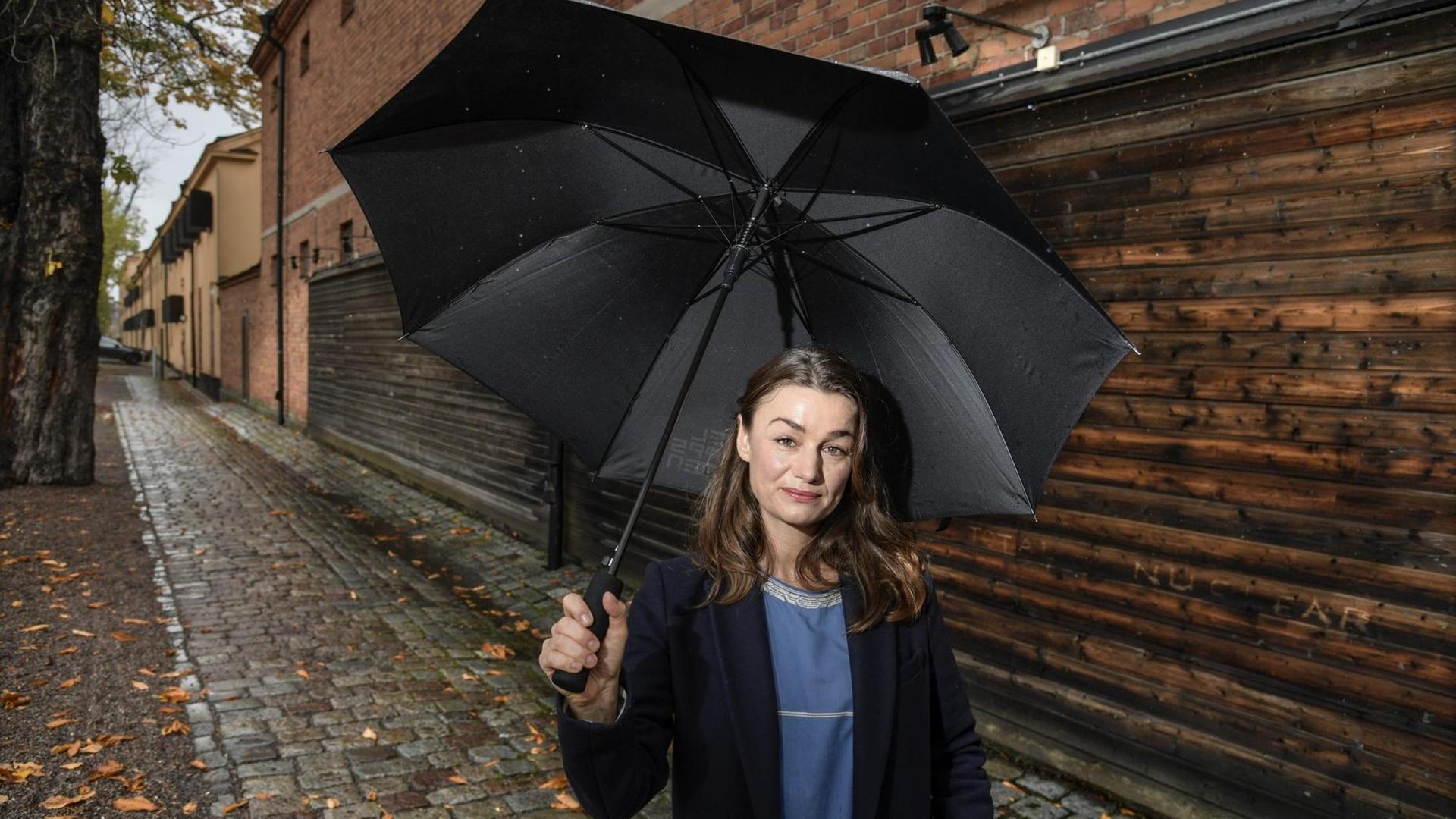 Johanna Adorján hält einen Regenschirm über sich.