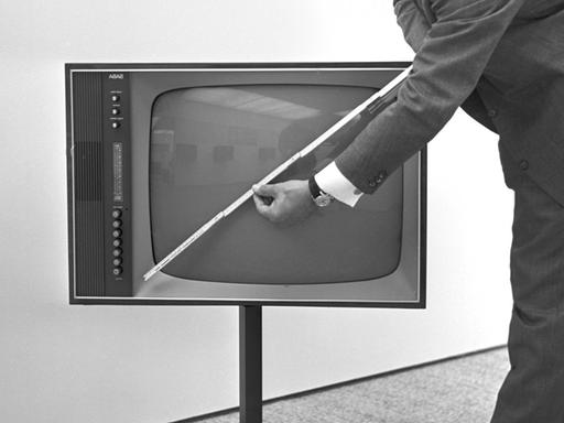 Ein Mann misst mit einem Zollstock einen Fernseh-Bildschirm