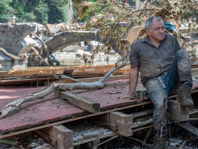 Ein Helfer ruht sich auf Treibgut und Trümmern aus. Zahlreiche Häuser in dem Ort wurden komplett zerstört oder stark beschädigt.