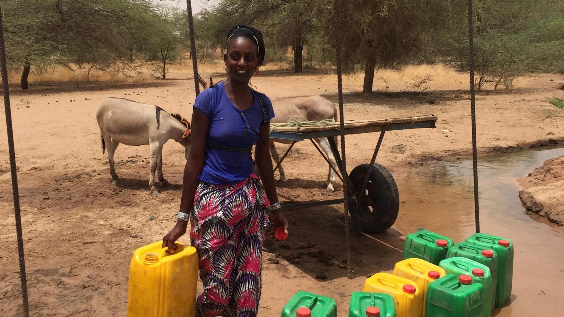 Ein junge Frau trägt einen Wasserkanister.