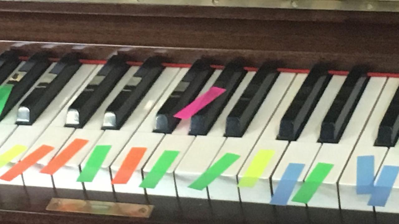Ein Klavier mit vielen bunten Post-Its.
