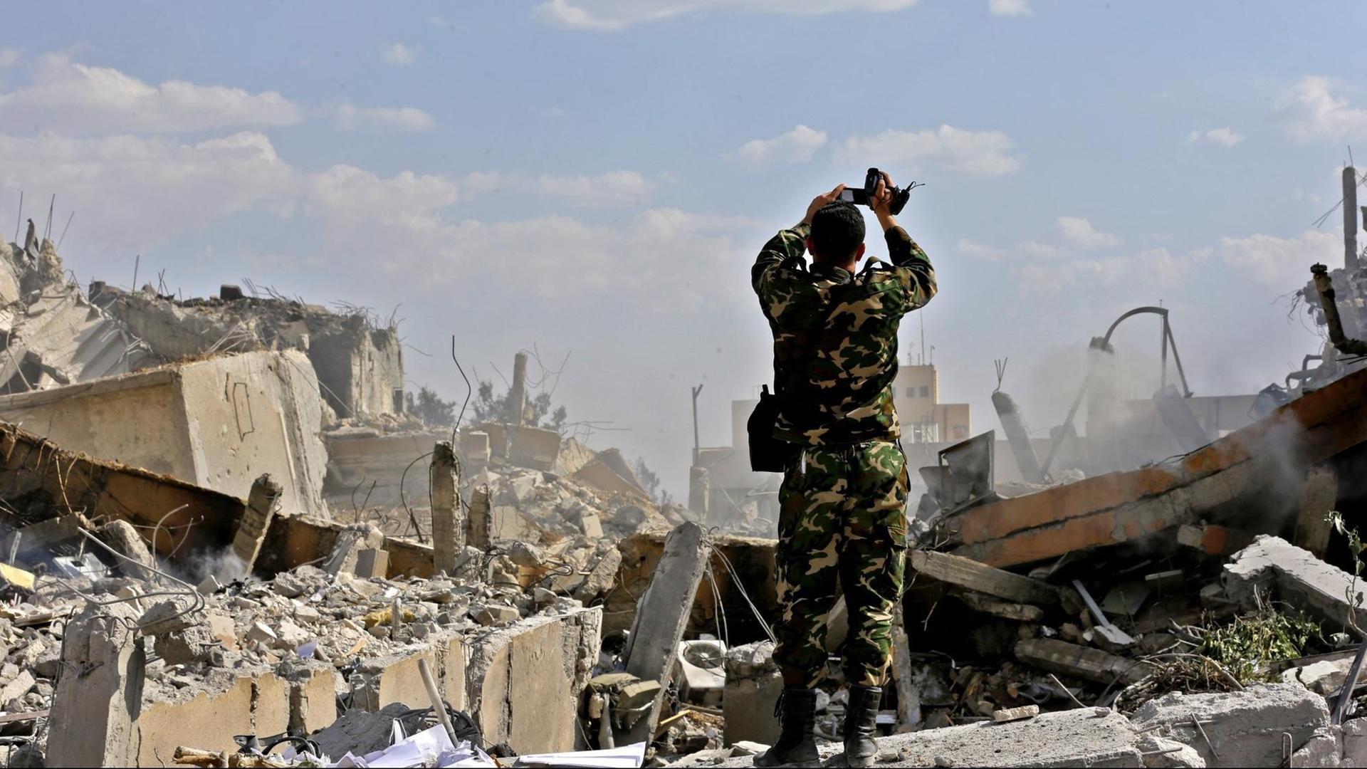 Ein syrischer Soldat filmt ein zerstörtes Gebäude des Forschungszentrums in Barzeh nördlich von Damaskus, das nach Angaben Syriens von den Luftschlägen der USA, Frankreichs und Großbritanniens getroffen worden sein soll