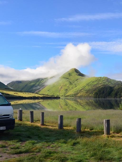 Ein Campingbus steht vor einem See und einer Berglandschaft in Neuseeland