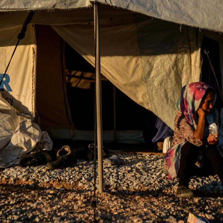 Eine Frau sitzt vor dem geöffneten Eingang eines UNHCR-Hilfszeltes im Flüchtlingscamp Kara Tepe 