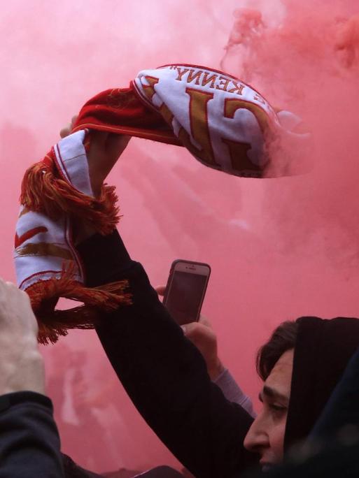 Ein FC Liverpool Fan mit Rauchbombe und Fanschal.