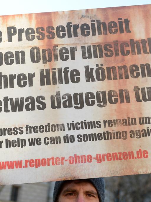 Ein Demonstrant der Organisation "Reporter ohne Grenzen" steht am 04.02.2014 vor der russischen Botschaft in Berlin. Er hält ein Schild hoch mit dem Text: "Ohne Pressefreiheit bleiben Opfer unsichtbar. Mit ihrer Hilfe können wir etwas dagegen tun.