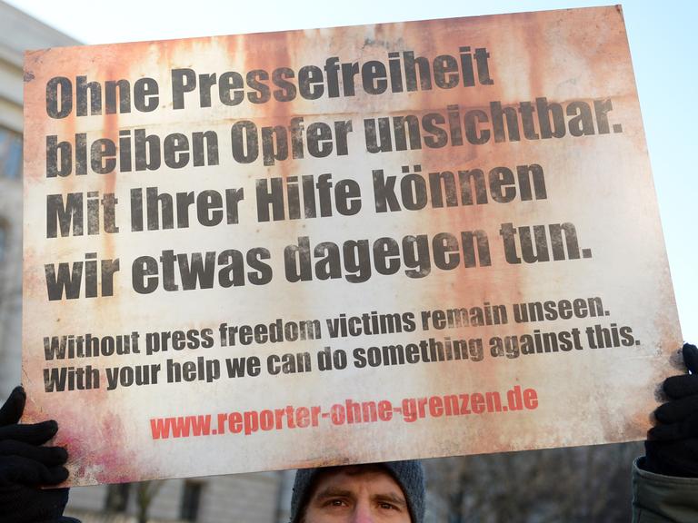 Ein Demonstrant der Organisation "Reporter ohne Grenzen" steht am 04.02.2014 vor der russischen Botschaft in Berlin. Er hält ein Schild hoch mit dem Text: "Ohne Pressefreiheit bleiben Opfer unsichtbar. Mit ihrer Hilfe können wir etwas dagegen tun.