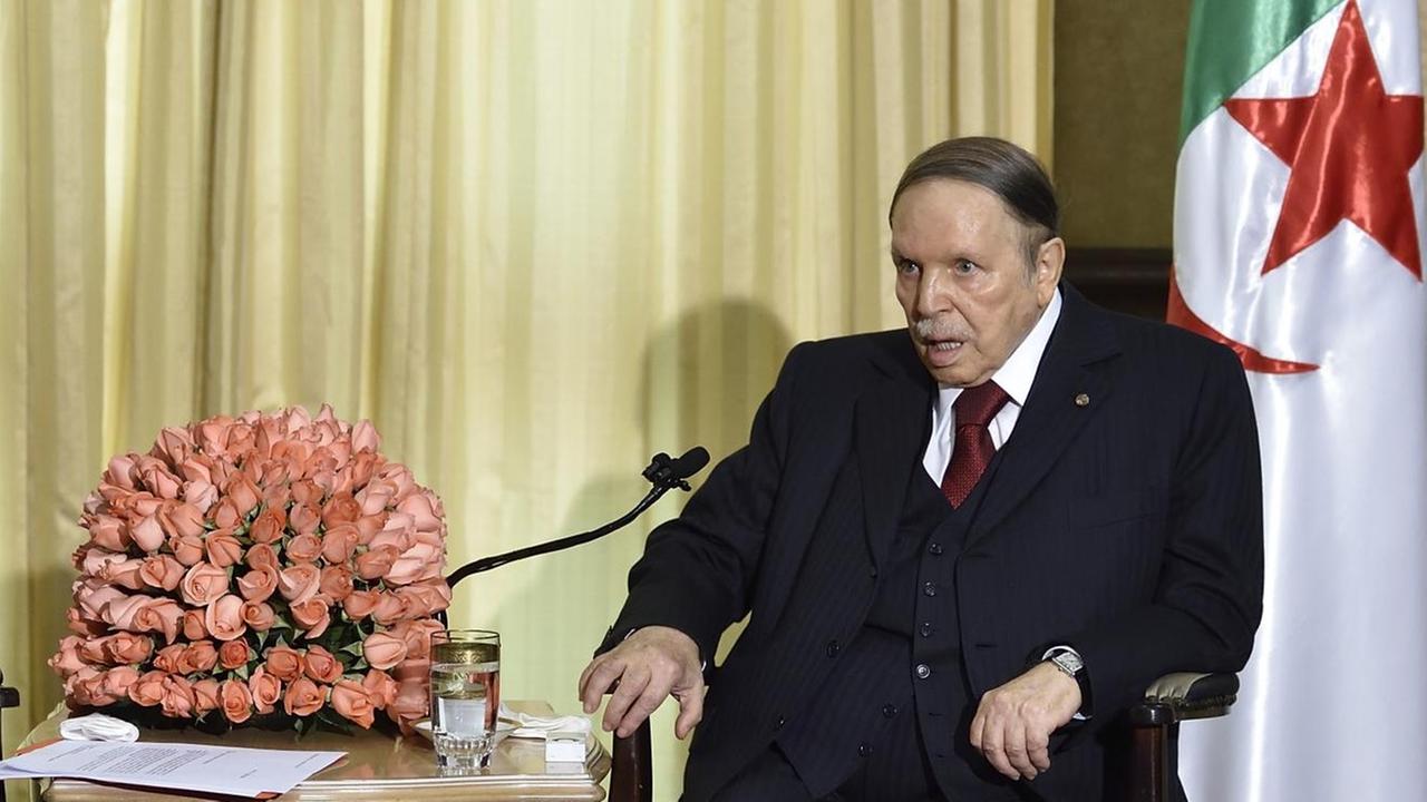 Ein Porträt von Bouteflika im Stuhl sitzend.