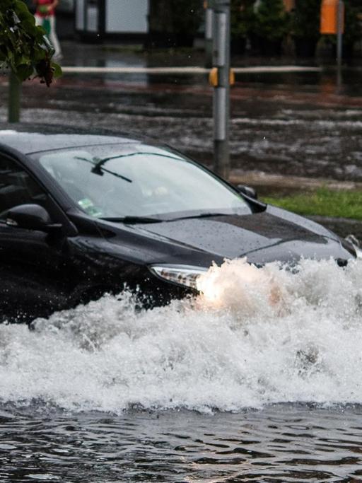 Ein Pkw fährt in Berlin nach einem Gewitter und starken Regenfällen durch die Wassermassen in der Breiten Straße.