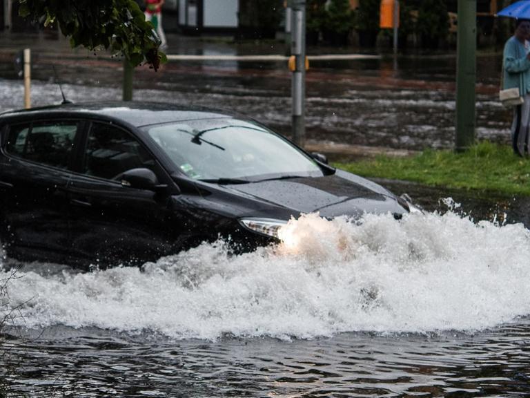 Ein Pkw fährt in Berlin nach einem Gewitter und starken Regenfällen durch die Wassermassen in der Breiten Straße.