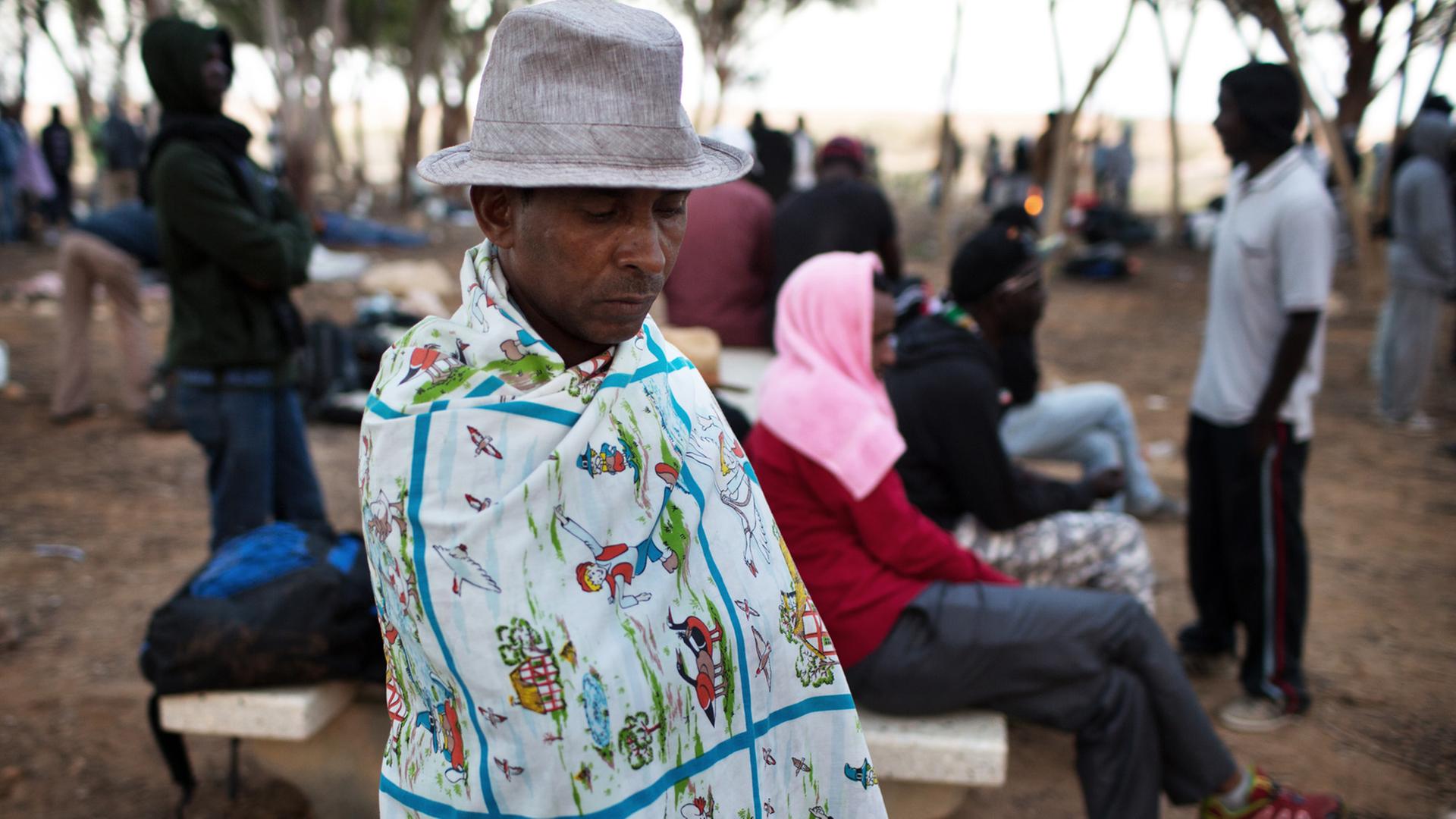 Ein afrikanischer Flüchtling hält sich ein buntes Tuch um den Körper.