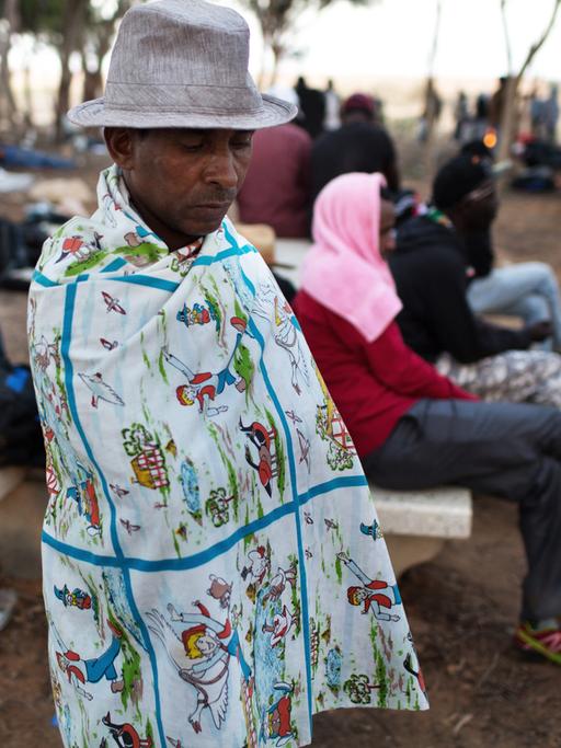 Ein afrikanischer Flüchtling hält sich ein buntes Tuch um den Körper.