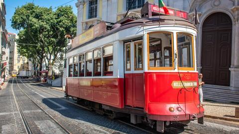 Eine alte Straßenbahn fährt durch Lissabons Altstadt.
