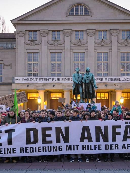 "Wehret den Anfängen - Keine Regierung mit Hilfe der AFD" steht auf einem Transparent, das Demonstranten vor dem Theater und dem Goethe- und Schillerdenkmal halten. Die Menschen demonstrieren gegen den neuen Ministerpräsidenten von Thüringen.