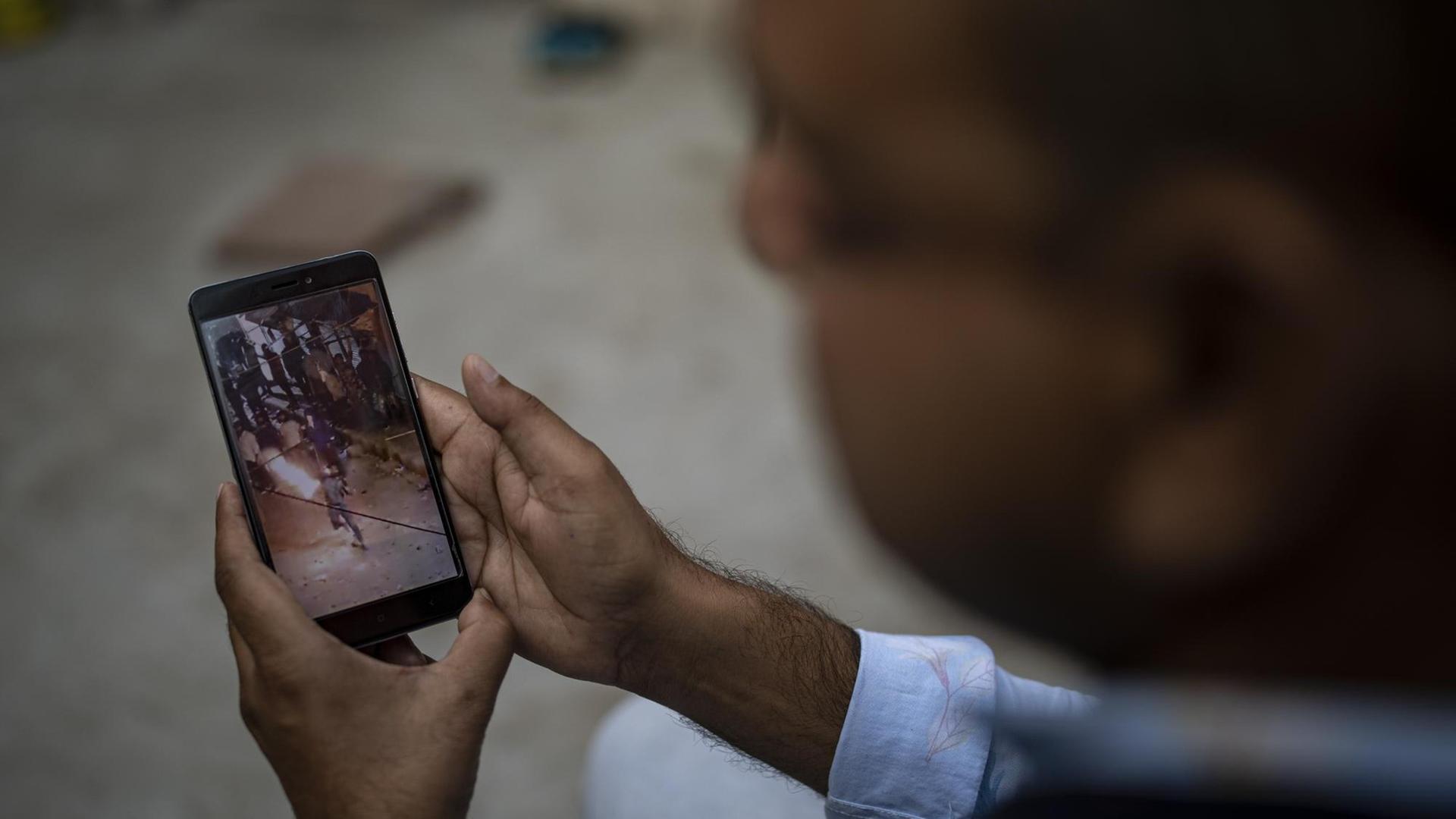 Muhammad Nasir Khan, who was shot by a Hindu mob during the February 2020 communal riots, watches a video showing a Hindu mob throwing petrol bomb towards a Muslim house in North Ghonda, one of the worst riot affected neighborhood, in New Delhi, India, Friday, Feb. 19, 2021. As the first anniversary of bloody communal riots that convulsed the Indian capital approaches, Muslim victims are still shaken and struggling to make sense of their struggle to seek justice. (AP Photo/Altaf Qadri)