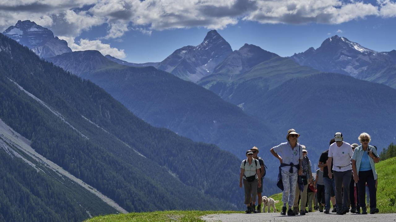 Mehrere Menschen laufen bei einem Spaziergang während des Davos Festivals 2020 vor Schweizer Bergkulisse.