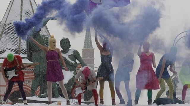 Ein halbes Dutzend maskierte Tänzer und Musiker am Roten Platz, Rauchschwaden steigen auf
