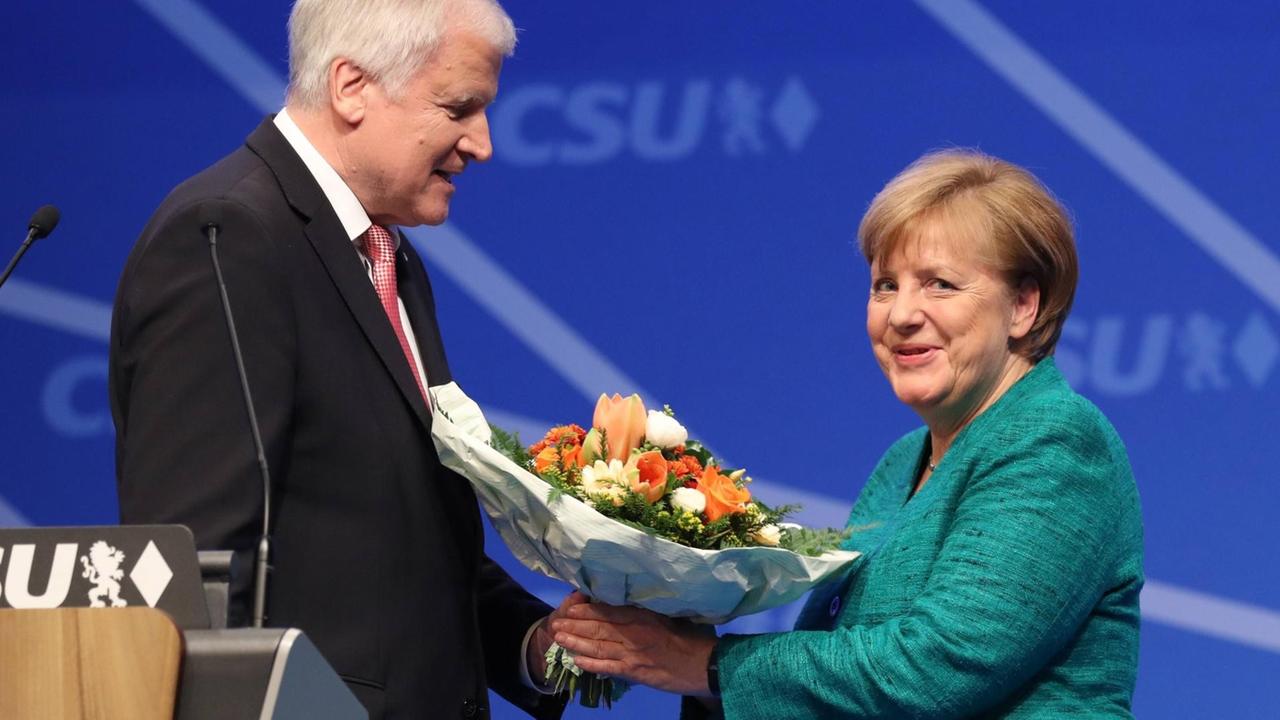 CSU-Chef Horst Seehofer und die CDU-Vorsitzende Angela Merkel beim CSU-Parteitag in Nürnberg, Seehofer überreicht Blumen an Merkel.
