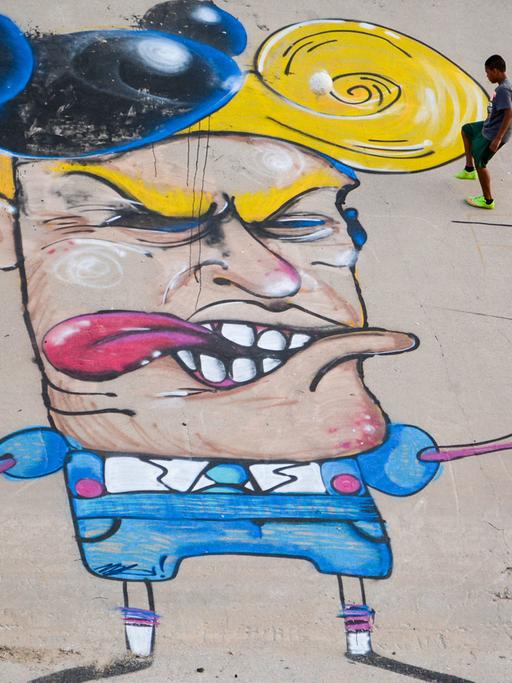 Kinder spielen am 23.06.2016 neben einer Graffiti-Karikatur, die Donald Trump im Flussbett des Rio Grande, zeigt.
