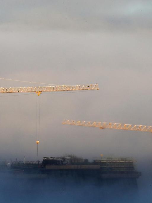 Zwei Baukräne im Nebel bauen das Lambda, das neue Munch-Museum in Oslo.