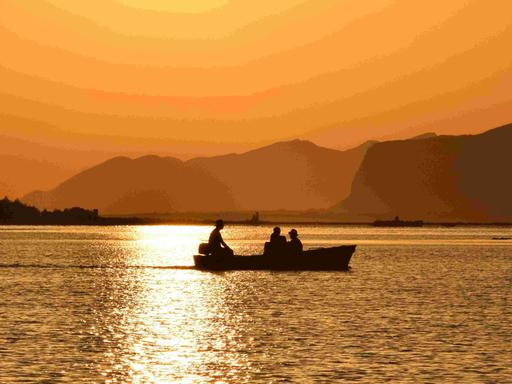 Sizialianische Küste: Silhouette eines Boots vor orangenem Sonnenuntergang. 