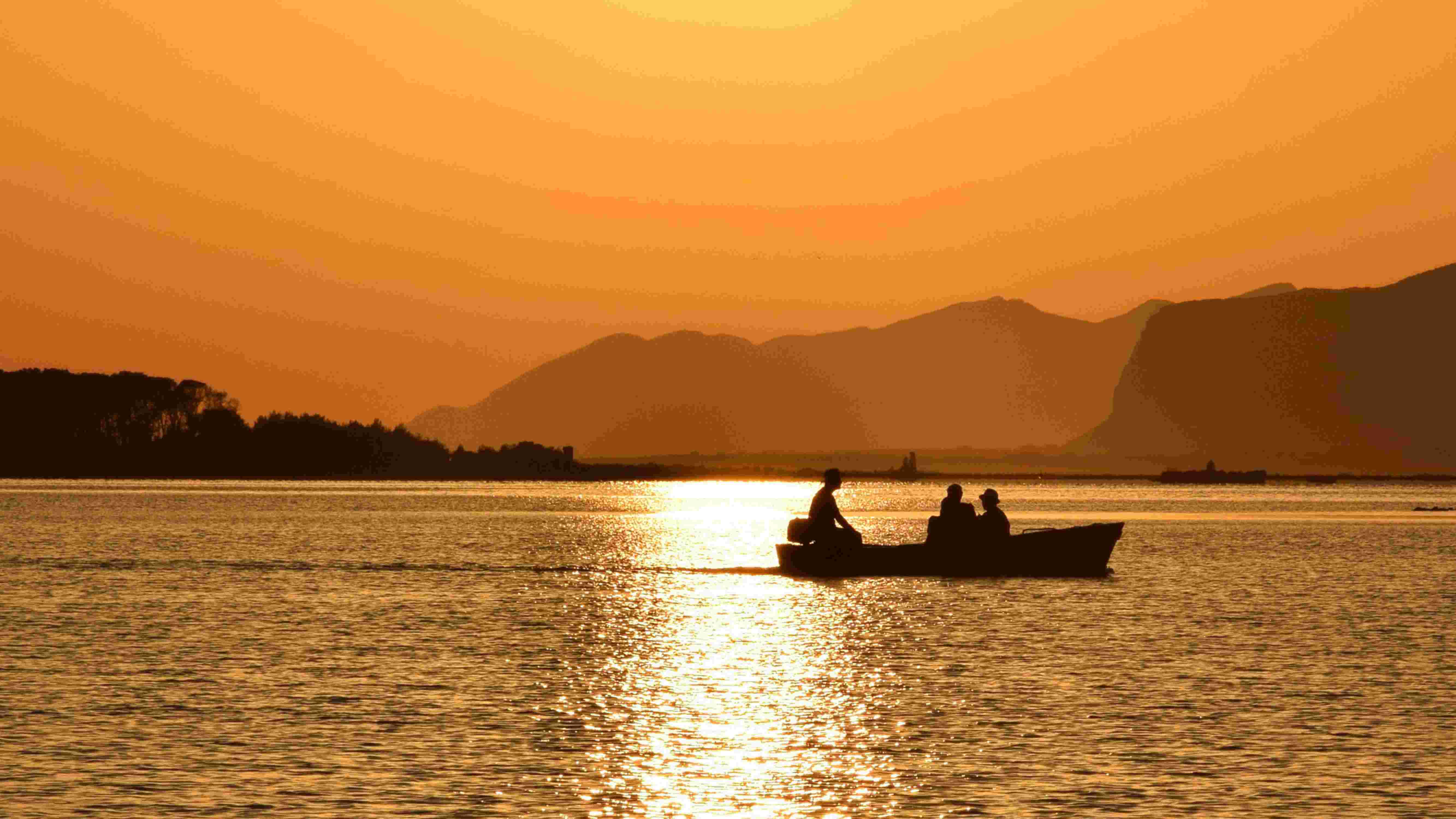 Sizialianische Küste: Silhouette eines Boots vor orangenem Sonnenuntergang. 