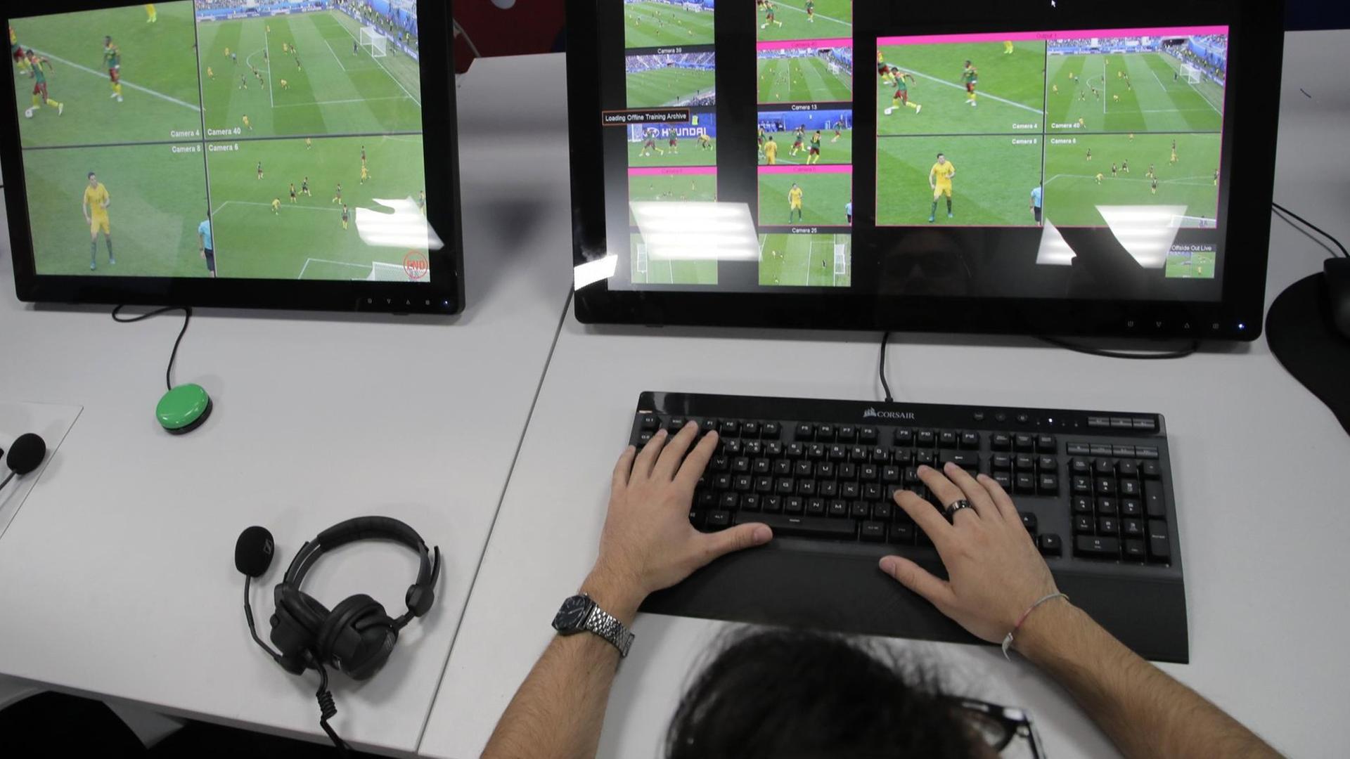 Ein Video-Assistent sitzt vor Bildschirmen, auf denen ein Fußball-Spiel zu sehen ist Ein Video-Assistent sitzt vor Bildschirmen, auf denen ein Fußball-Spiel zu sehen ist