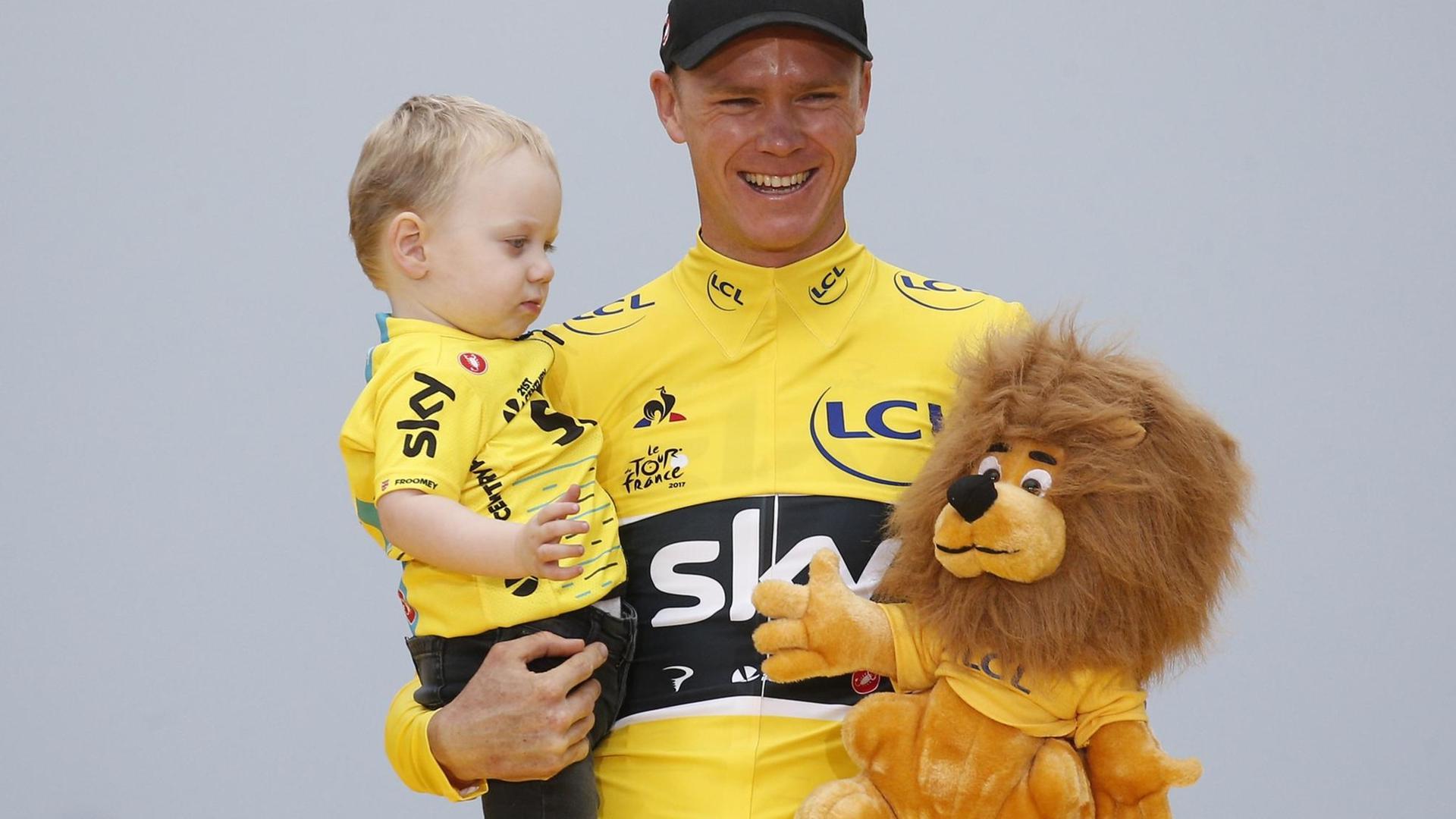 Der Brite Christopher Froome vom Team Sky im Gelben Trikot des Gesamtführenden bejubelt auf dem Podium den Gesamtsieg mit seinem Sohn Kellan.
