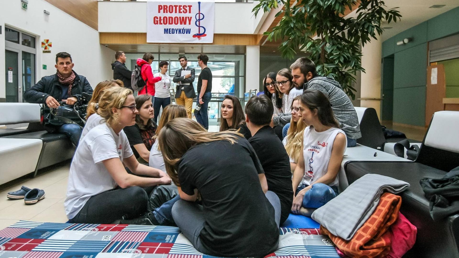 Hungerstreik in Polen: Junge Ärztinnen und Ärzte sitzen in einer Klinik auf Matratzen auf dem Boden