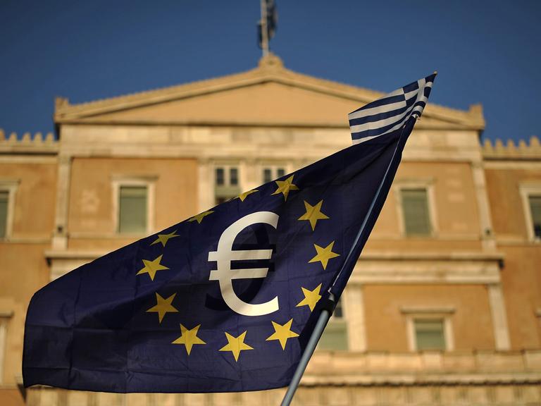 EU-Flagge mit Eurosymbol und einer kleinen griechischen Flagge vor dem Parlament in Athen