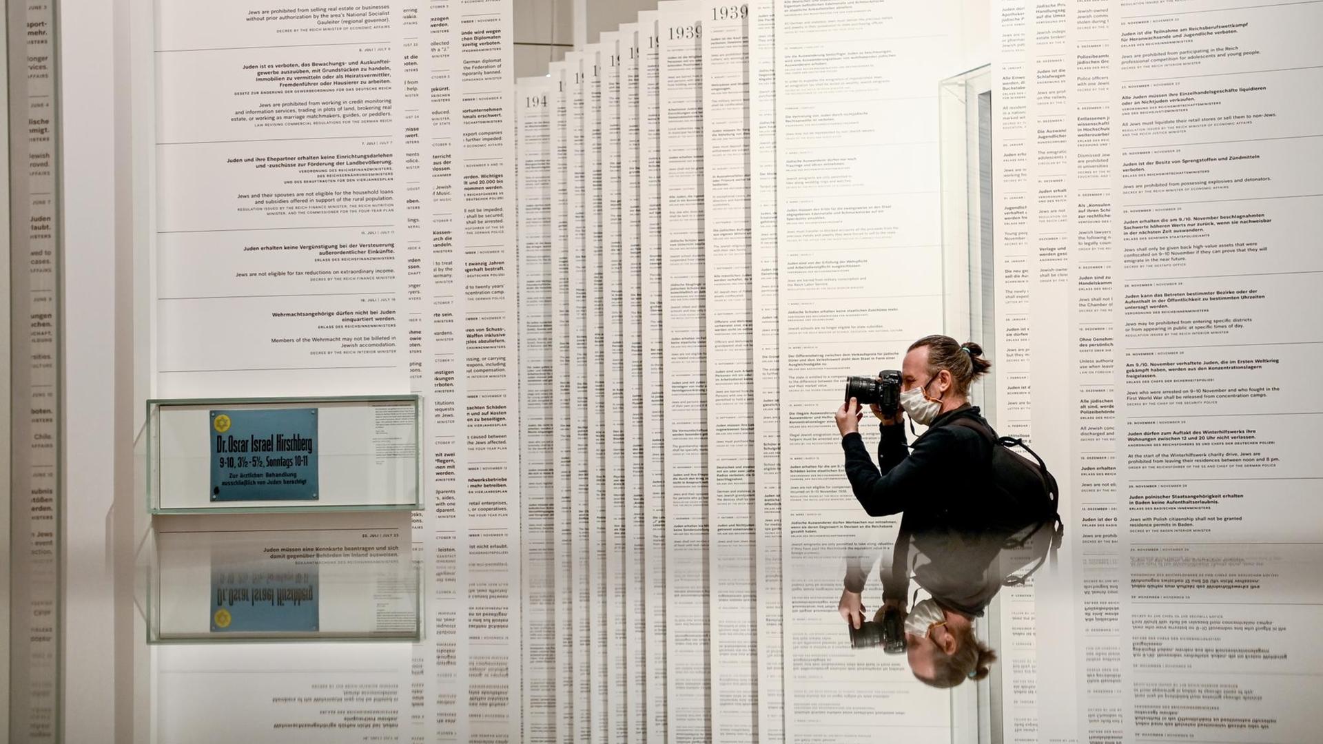 Ein Mann fotografiert im Jüdischen Museum die meterhohen weißen Papierfahnen, auf denen 962 Verordnungen aufgelistet sind, die von 1933 an gegen Juden erlassen wurden.