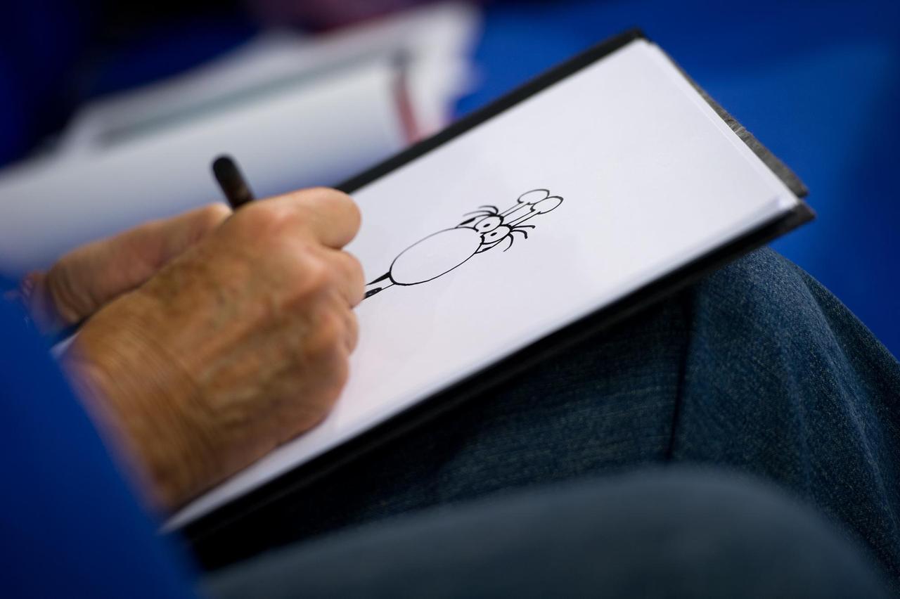 Der argentinische Zeichner Guillermo Mordillo ist am 13.10.2012 zu Gast auf dem sogenannten Blauen Sofa auf der Buchmesse in Frankfurt am Main und zeichnet eine Giraffe. Zu sehen ist seine Hand, die auf einen Blatt Papier eine Zeichnung anfertig. Mordillo stellte sein Buch "4 x 20 Jahre jung" vor. 