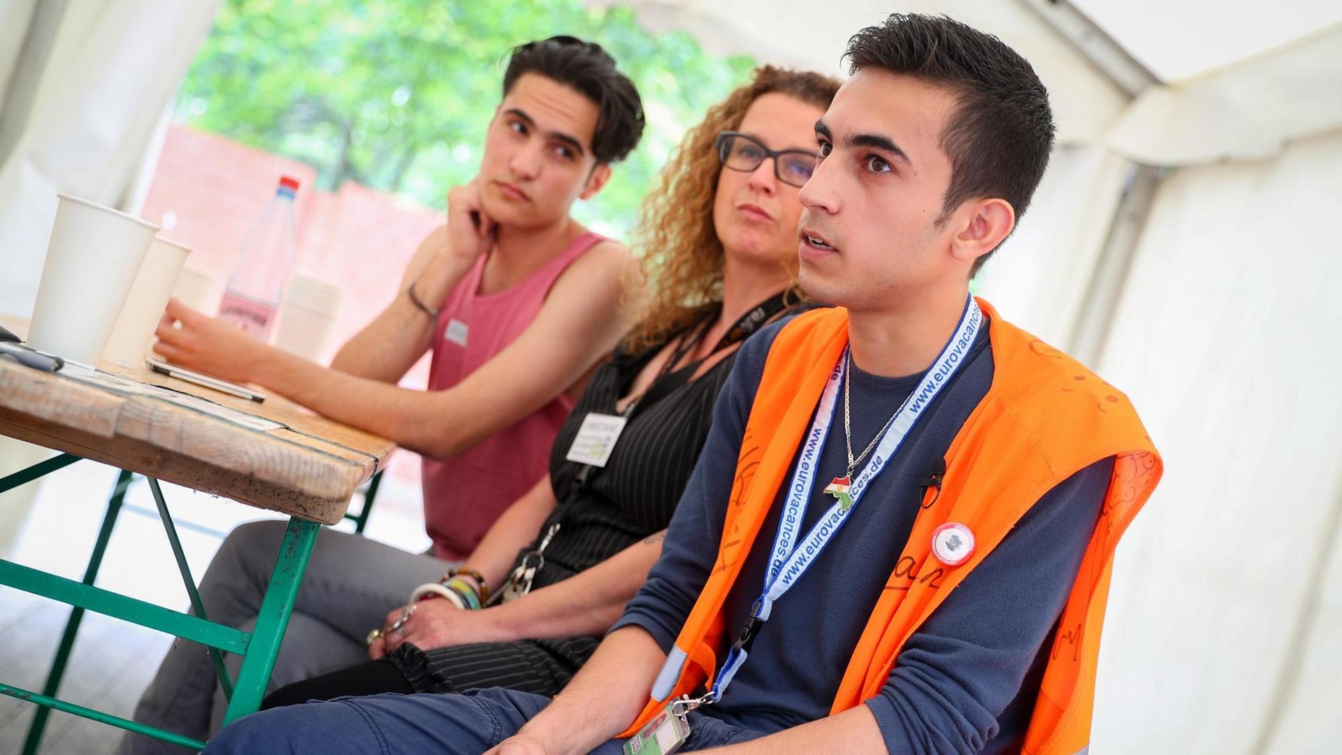 Ein 20-jähriger Syrer sitzt mit Helfern zusammen