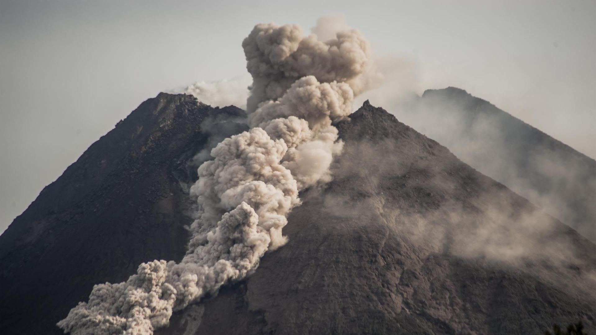 Eine langgezogene Wolke aus Rauch und Asche strömt aus dem Krater des Berges.