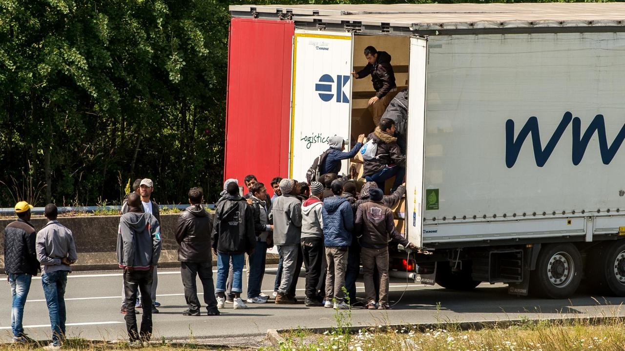 Flüchtlinge entern einen Lkw, der von Frankreich über den Eurotunnel nach Großbritannien will.