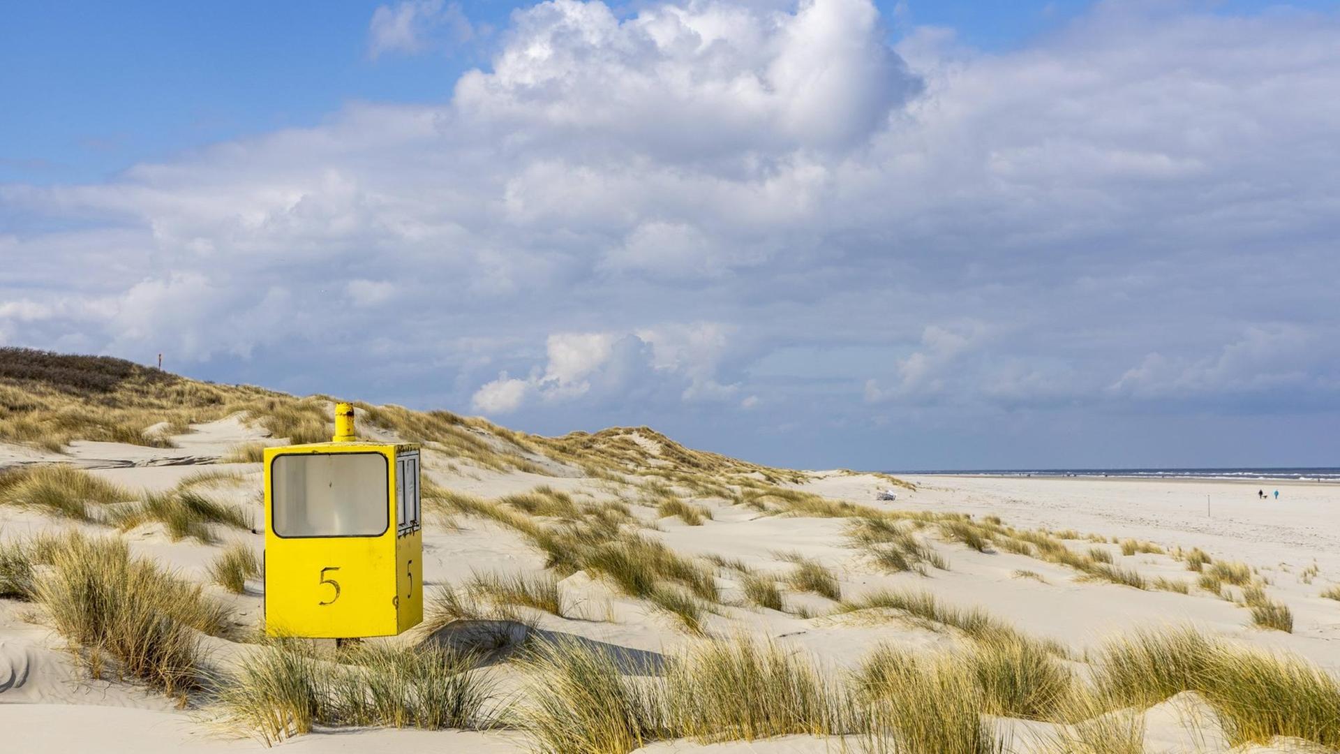 Ein gelber Aufsichtsturm in den Dünen am Wattenmeer.