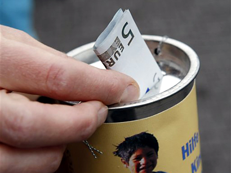 Eine Passantin steckt in Stuttgart einen Geldschein in die Sammelbüchse eines Kinderhilfswerks.