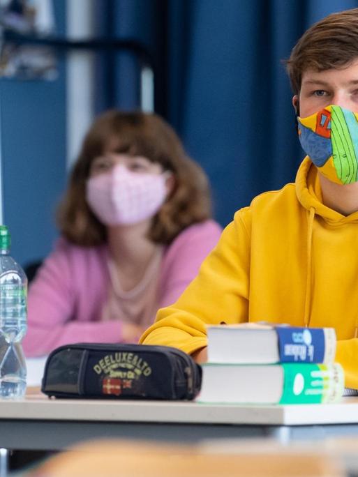 27.04.2020, Bayern, Unterhaching: Schüler und Schülerinnen einer 12. Klasse des Lise-Meitner-Gymnasiums nehmen am Unterricht teil und tragen Mundschutze.