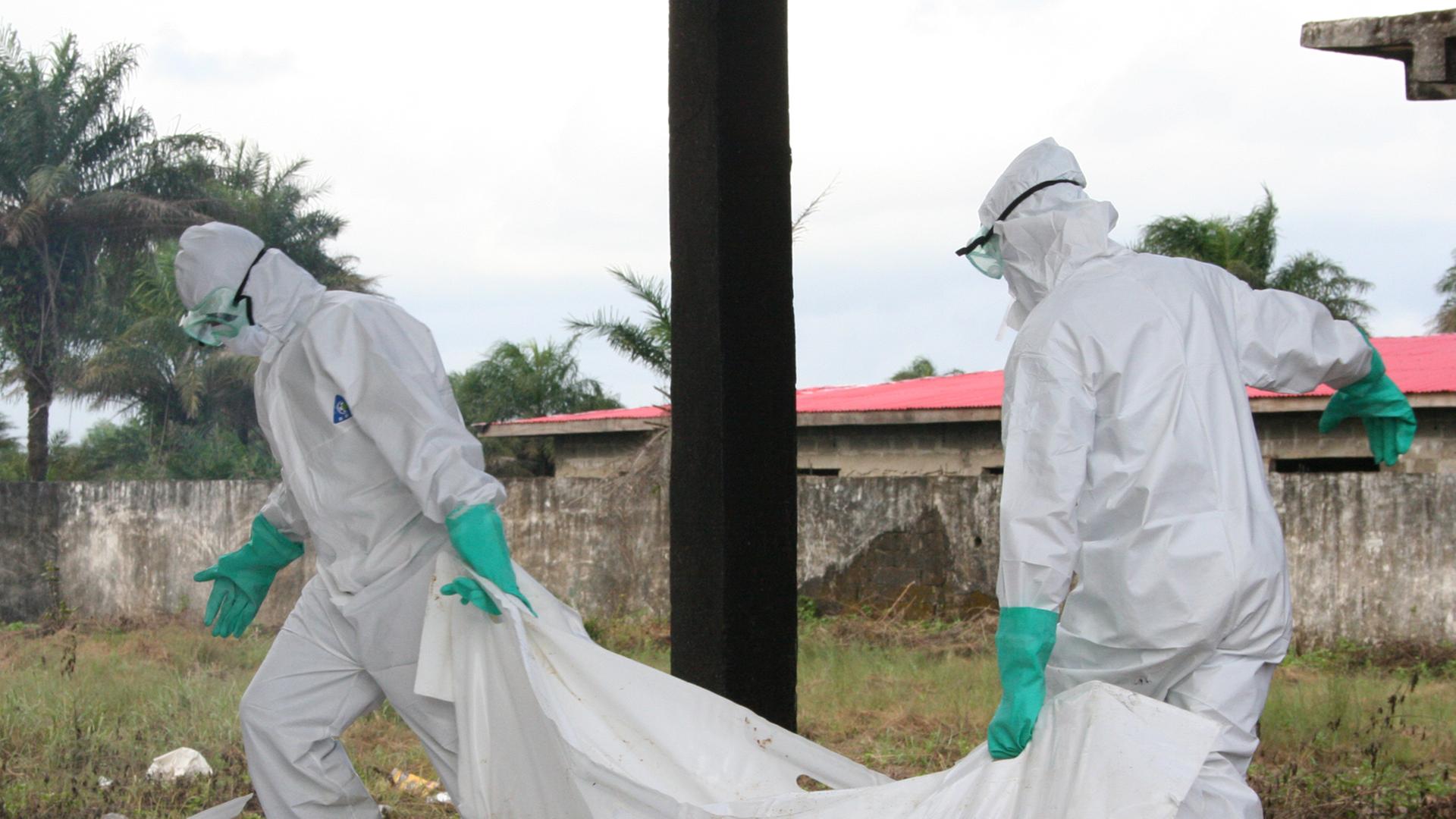 Mitarbeiter von Ärzte ohne Grenzen/Medecins Sans Frontieres (MFS), desinfizieren am 02.09.2014 in Schutzkleidung am Ebola Zentrum der Hilfsorganisation in Monrovia, Liberia, Leichensäcke.