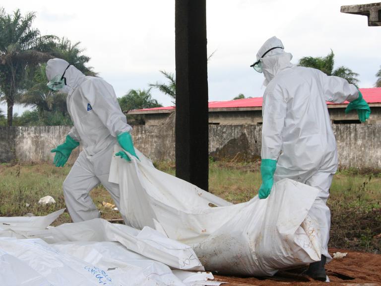 Mitarbeiter von Ärzte ohne Grenzen/Medecins Sans Frontieres (MFS), desinfizieren am 02.09.2014 in Schutzkleidung am Ebola Zentrum der Hilfsorganisation in Monrovia, Liberia, Leichensäcke.