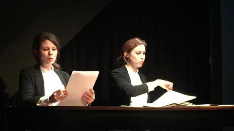 Die beiden Künstlerinnen während der Aufführung an einem Tisch und blicken konzentriert in ihre Partiture
