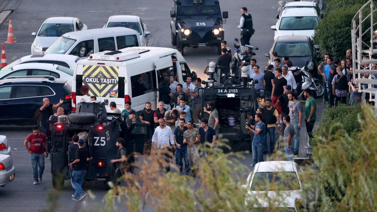 Sie sehen viele Menschen auf dem Taksim-Platz in Istanbul, außerdem Polizei- und Militärfahrzeuge.