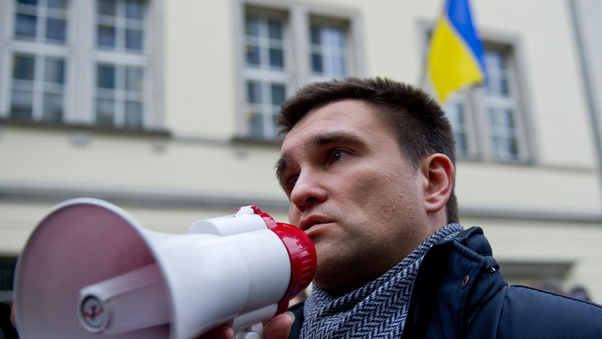 Der ukrainische Botschafter in Deutschland, Pavlo Klimkin, spricht in ein Megaphon, im Hintergrund mehrere Menschen und das Botschaftsgebäude mit der ukrainischen Flagge