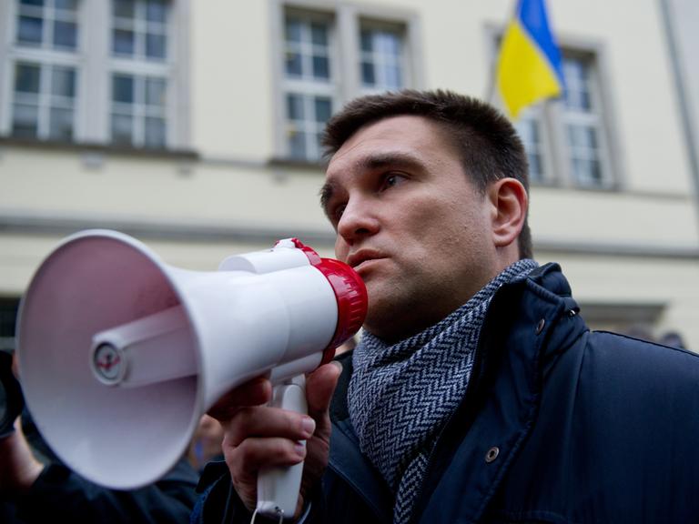 Der ukrainische Botschafter in Deutschland, Pavlo Klimkin, spricht in ein Megaphon, im Hintergrund mehrere Menschen und das Botschaftsgebäude mit der ukrainischen Flagge