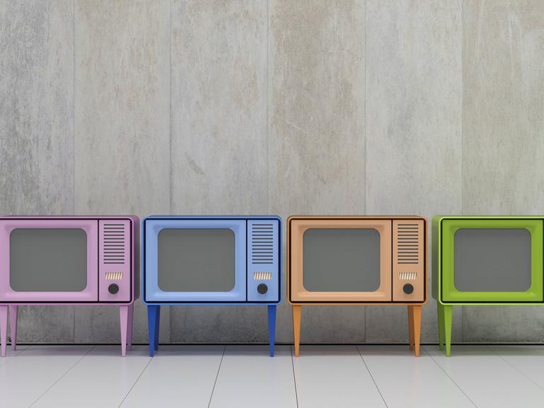 Vier Fernsehapparate im Retro-Style und in verschiedenen Farben stehen nebeneinander.